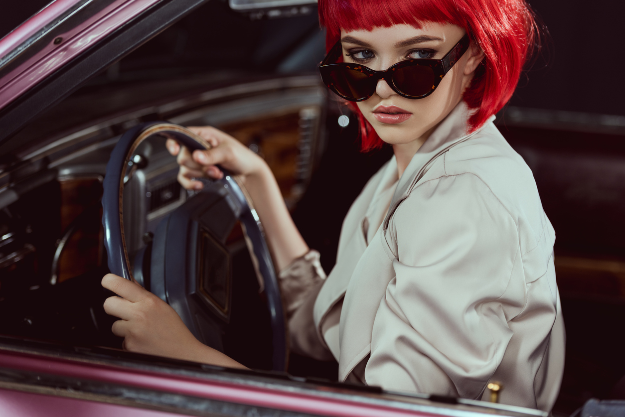 beautiful stylish girl in sunglasses driving retro car